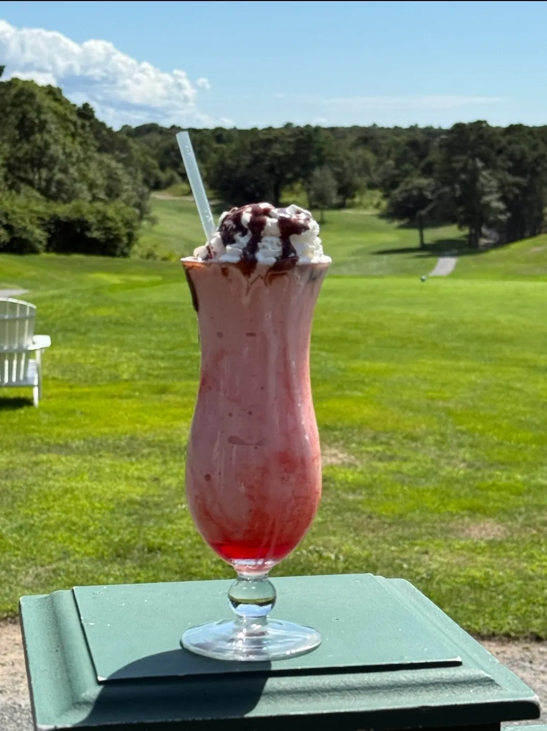 Frozen berry cocktail with whipped cream overlooking the green