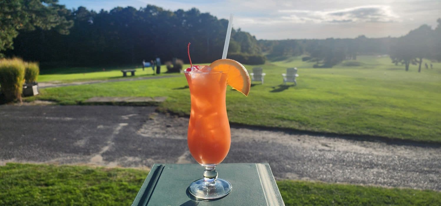 Orange sunset cocktail with cherry garnish on the patio